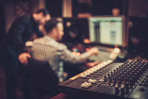 Sound engineer and producer working together at mixing panel in the boutique recording studio.